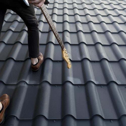 back-view-male-musician-climbing-roof-with-electric-guitar